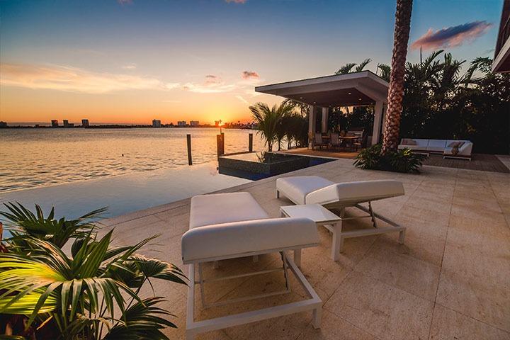 Luxury pool patio with lounge chairs at sunset in Naples at a luxury home rental